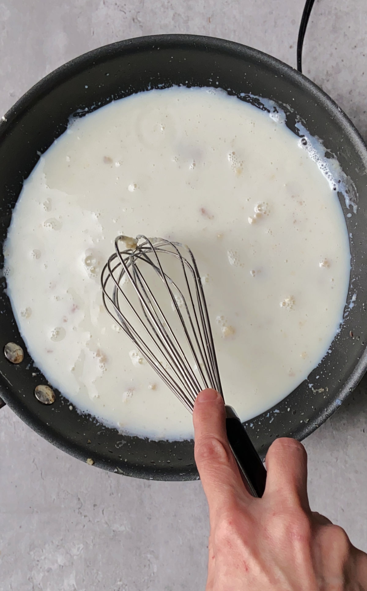 Whisking in the milk with the flour in a frying pan.