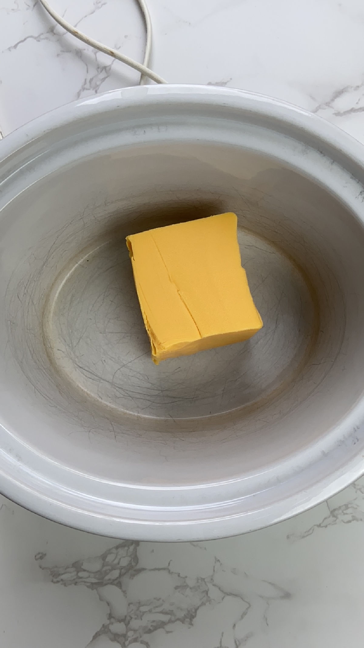 Block of Velveeta cheese in a crock pot. 