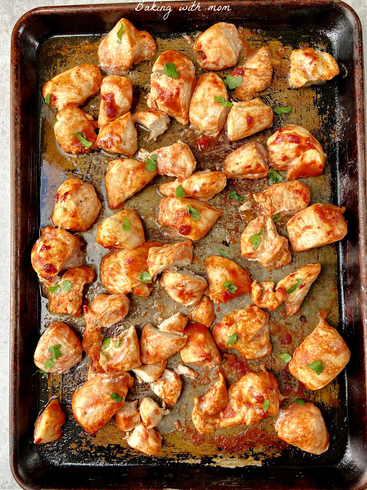 Chicken pieces with a marinade glaze and cilantro pieces on top. 