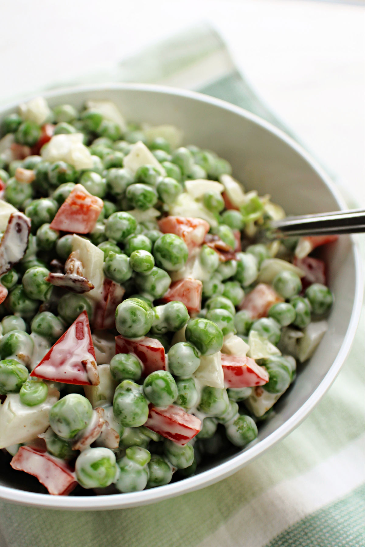 pea salad in a bowl with red peppers and onions in a white bowl. 