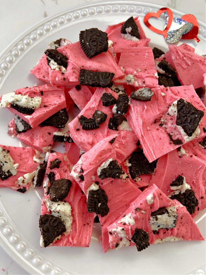 White plate with pink candy pieces on top made of almond bark. 