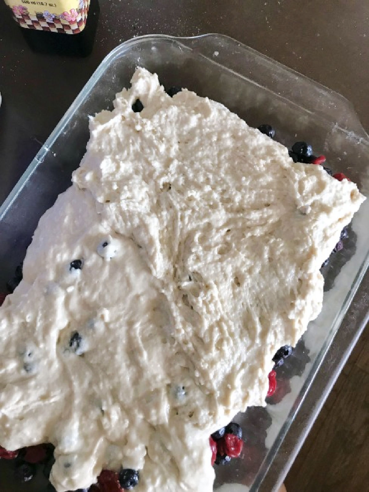 Unbaked cobbler dough on berries in a baking dish. 