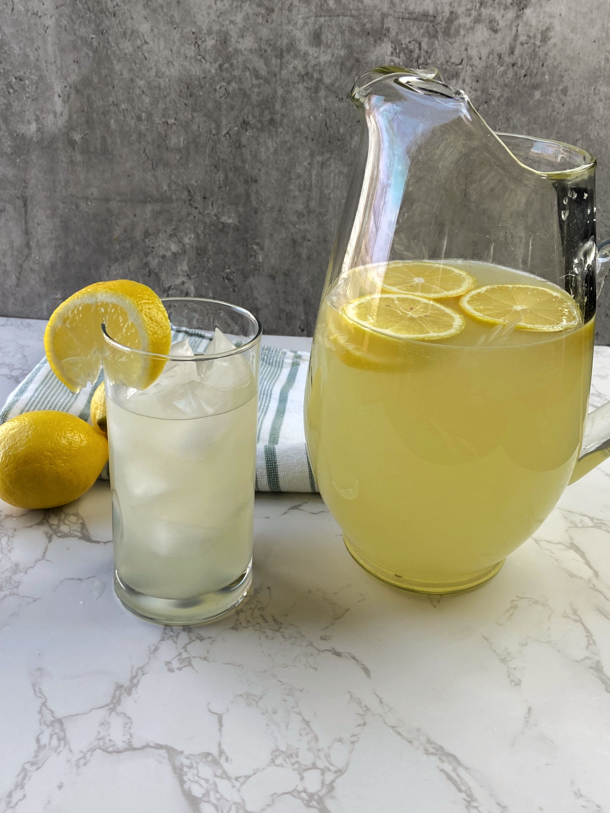 Pitcher of lemonade next to a glass of lemonade. 