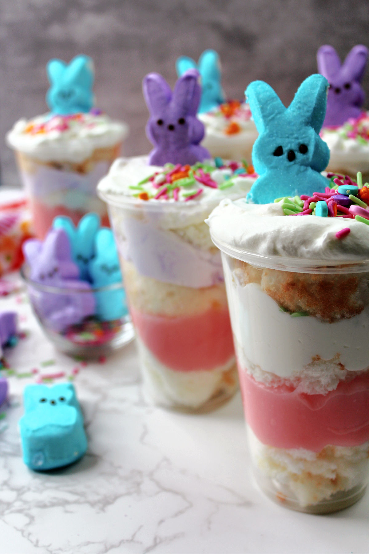 Cups of pudding, whipping cream and cake with peeps on top. 