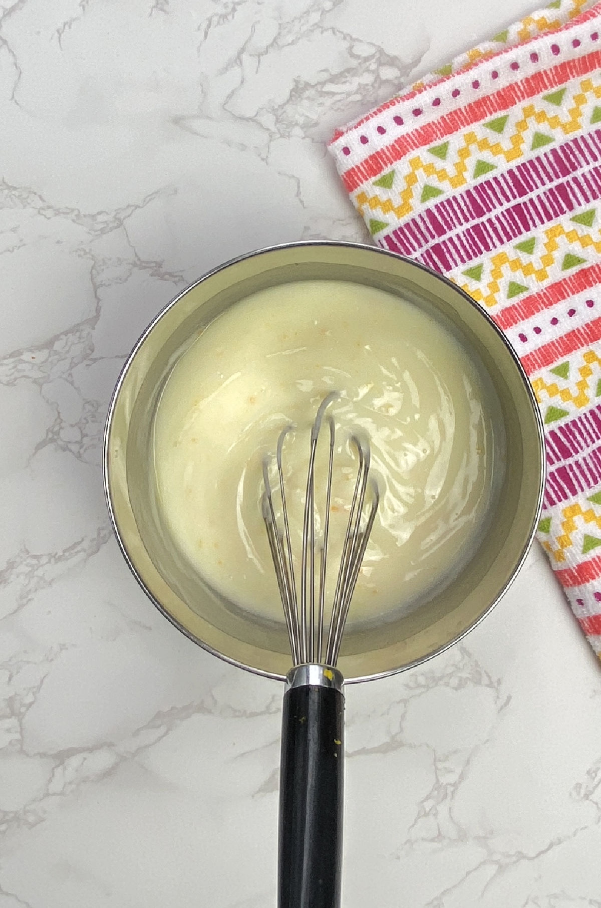 Silver bowl with yogurt and sugar with a whisk. 