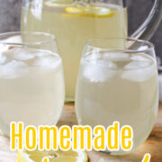 homemade lemonade in a clear pitcher with glasses in front.