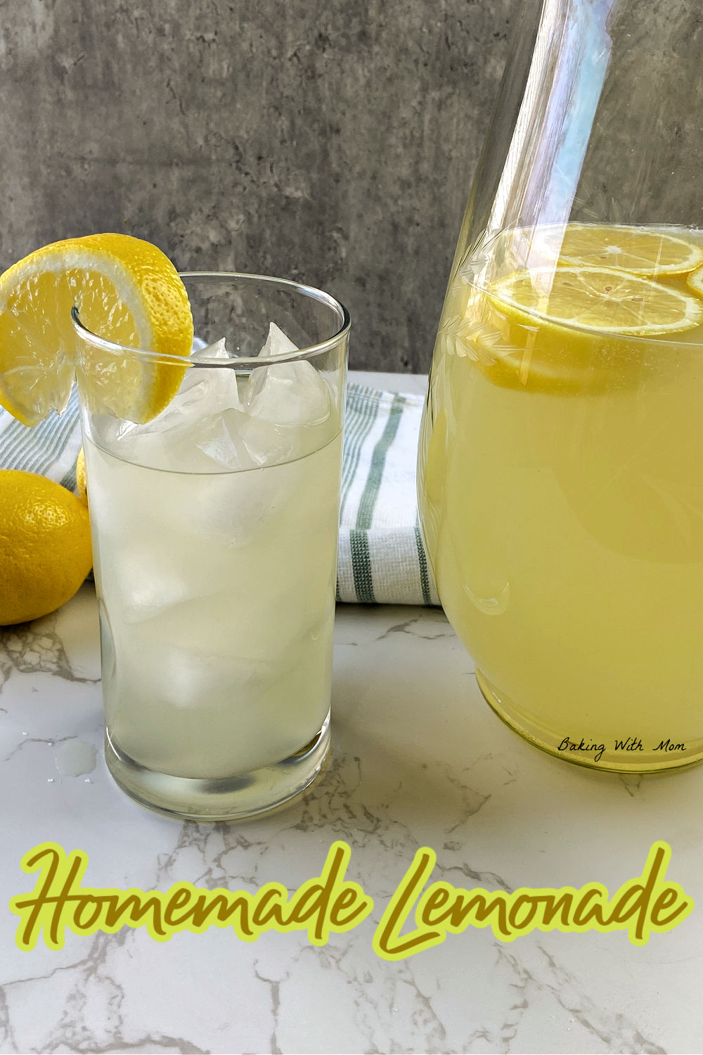 Pitcher of lemonade with a glass of lemonade besides and fresh lemons. 