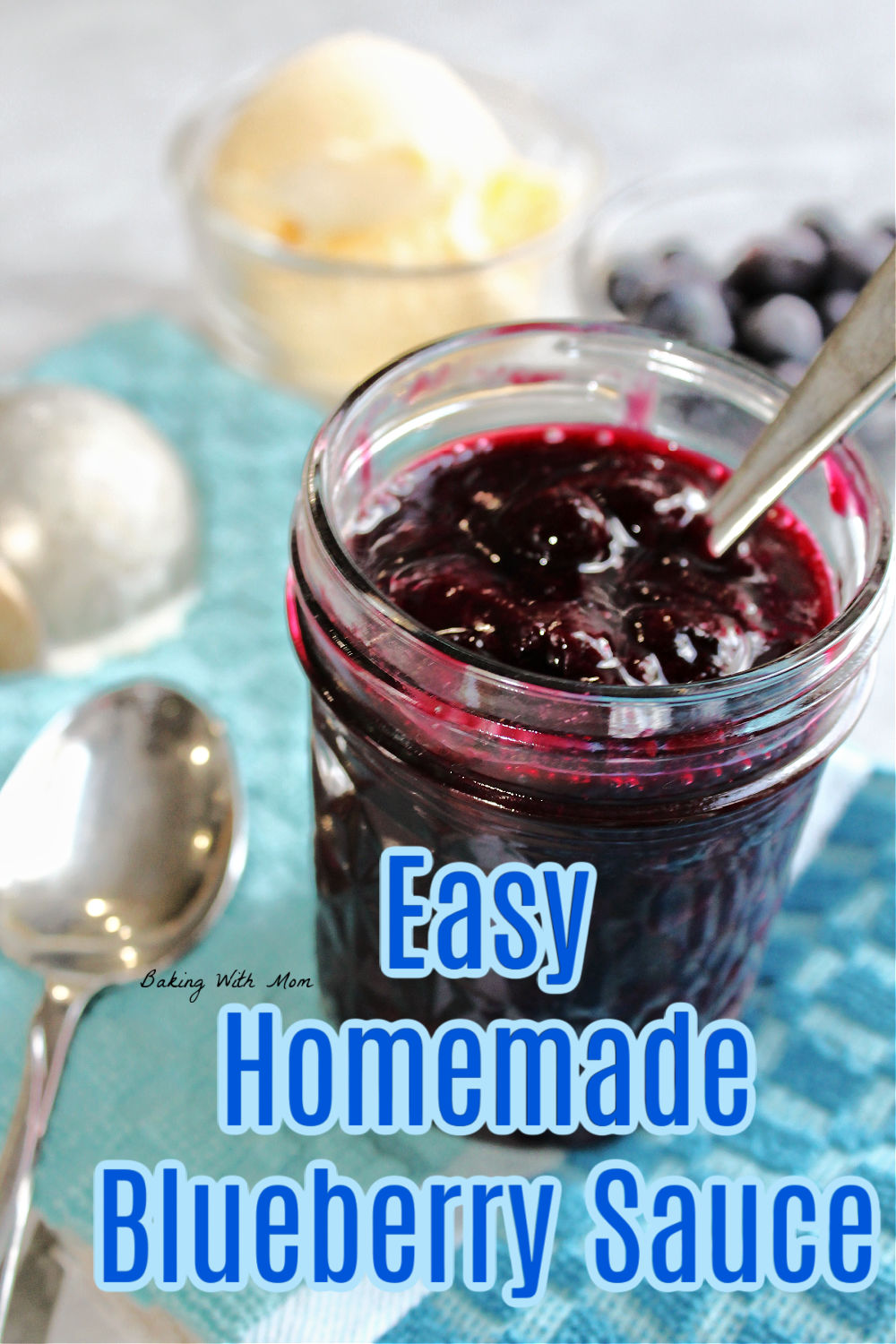 Blueberry sauce in a clear jar with a spoon laying besides. 