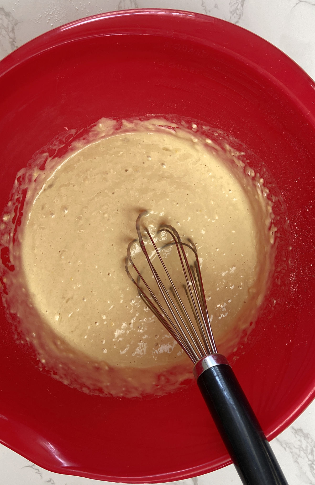 pancake batter in a red bowl with a whisk. 