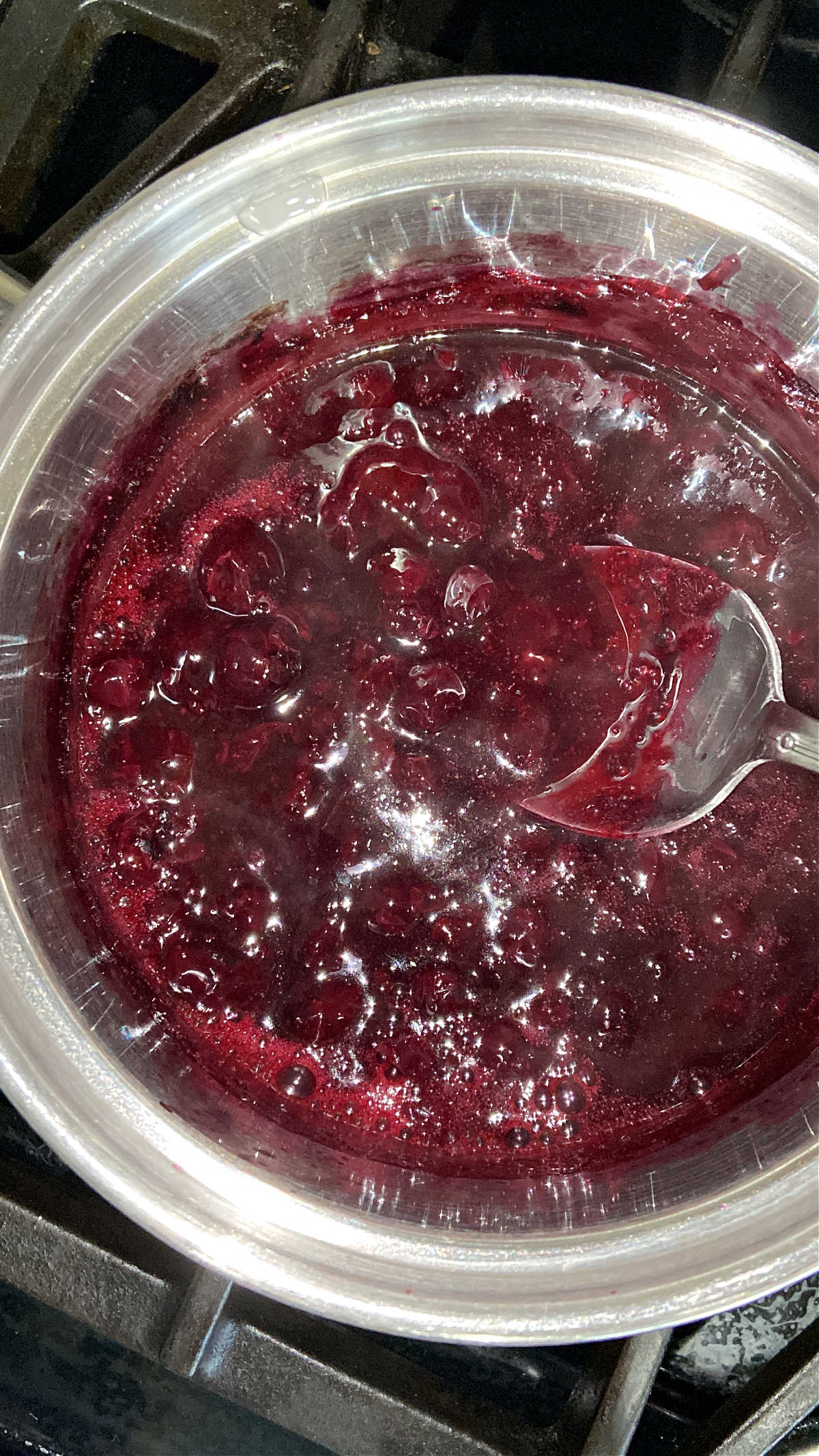 The thickened blueberry sauce in a pot on the stove. 