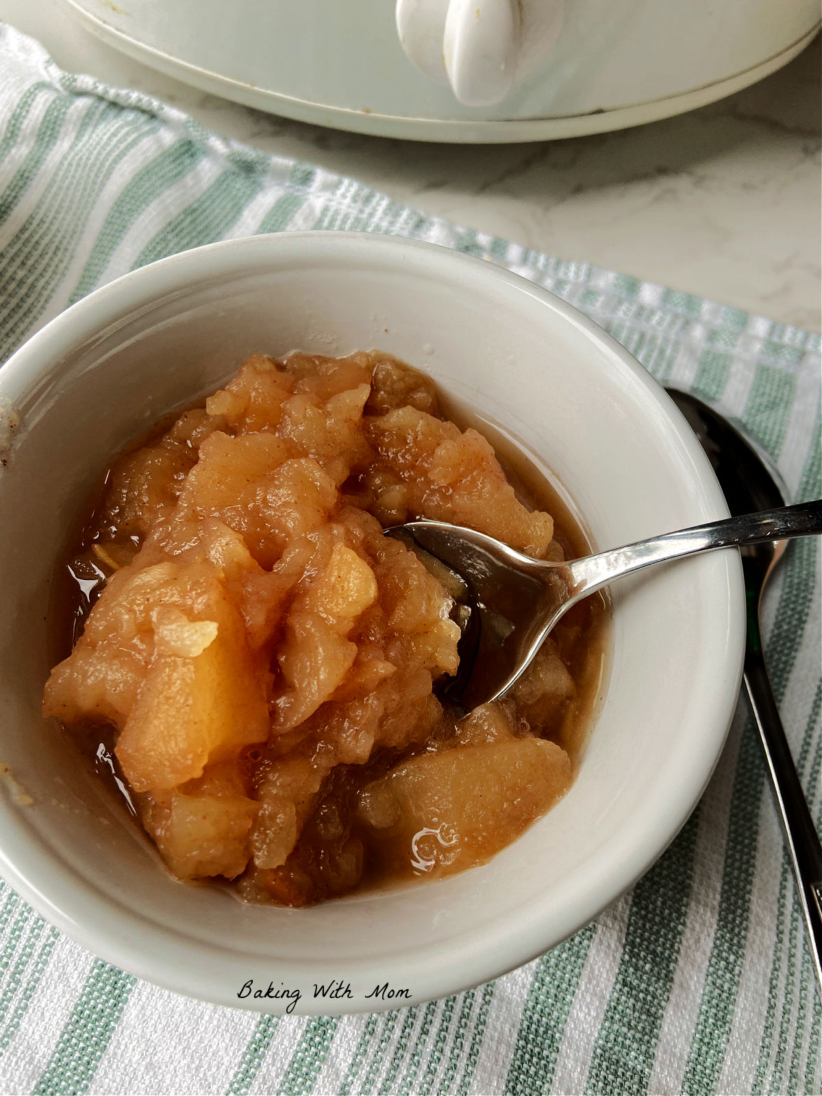 Bowl of chunky applesauce on a green striped towel. 