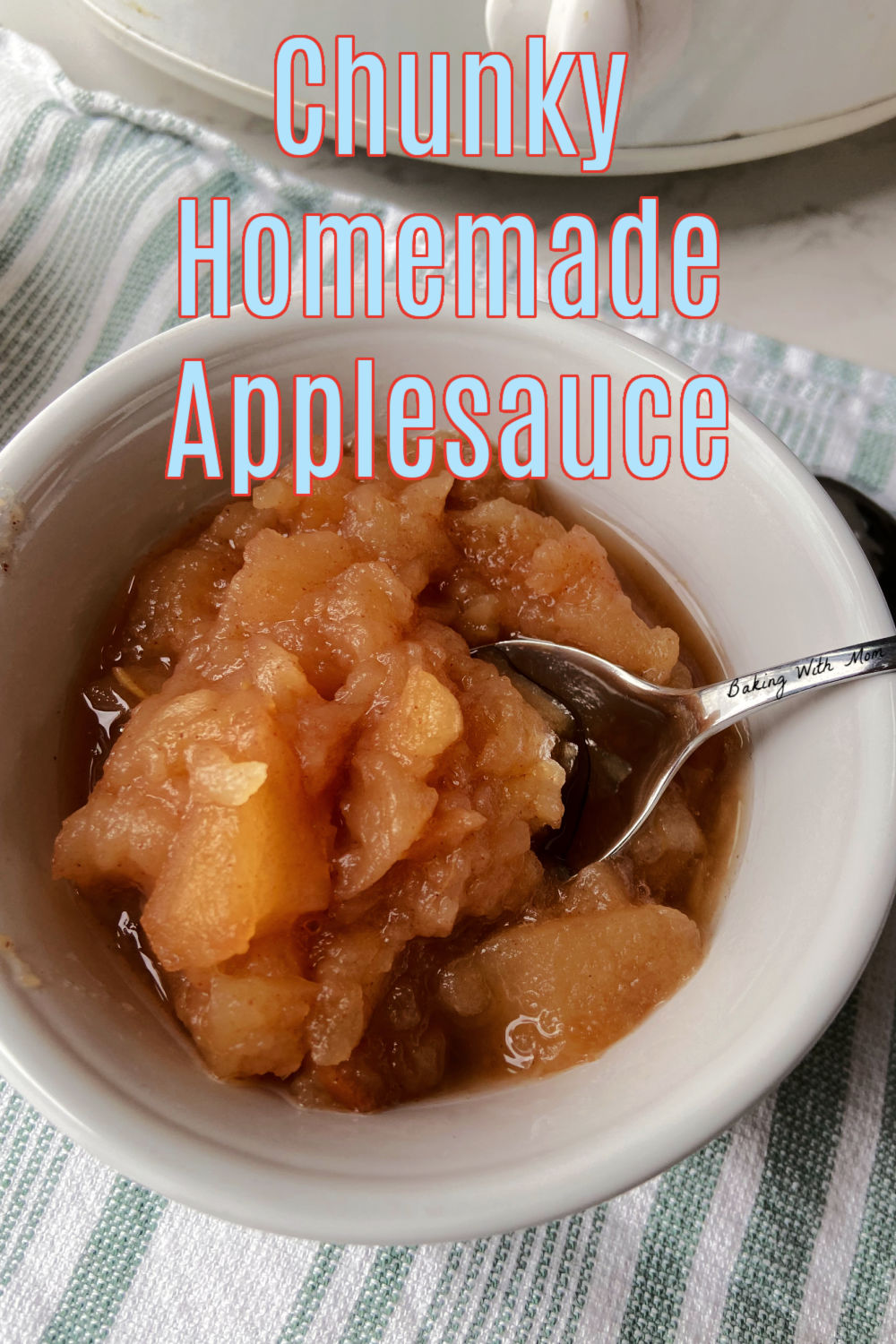 Applesauce in a white bowl with a spoon nearby. 