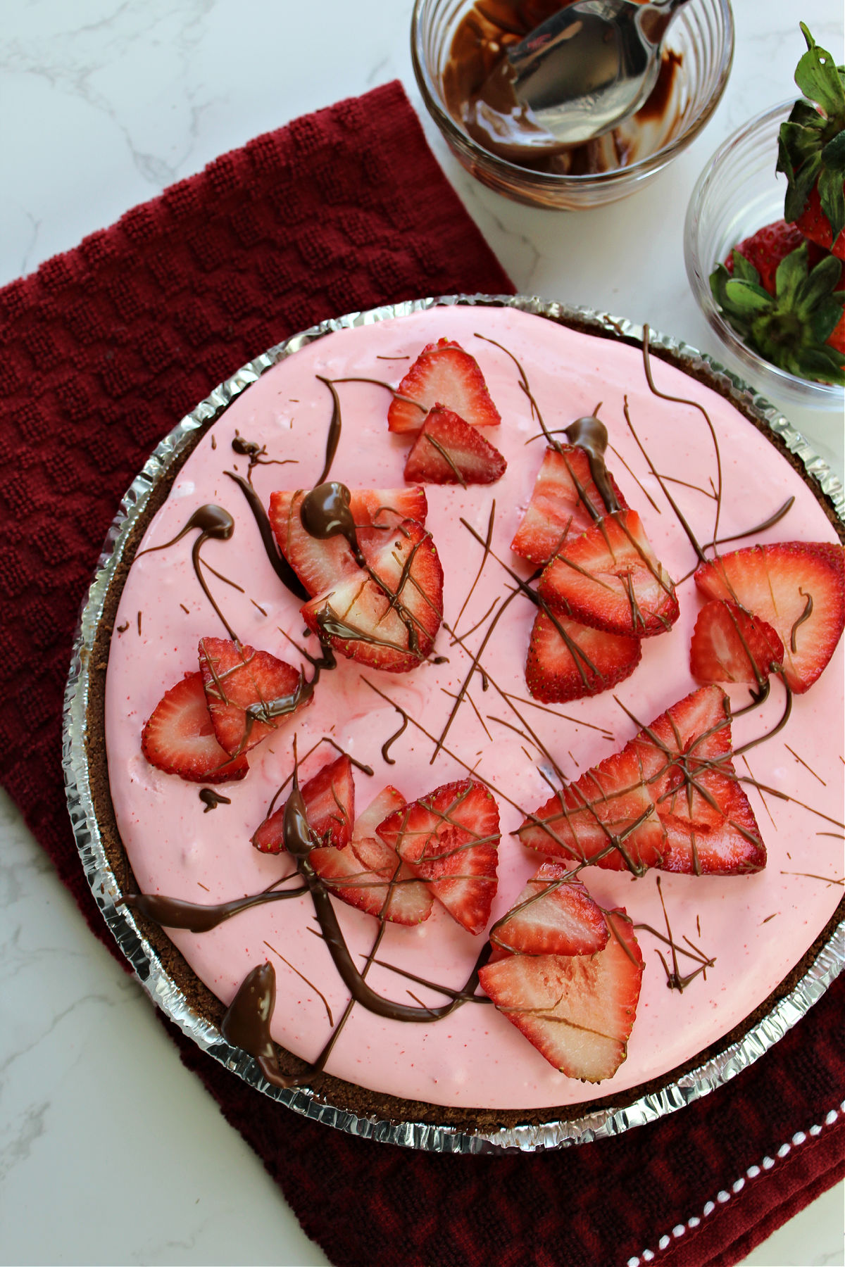 chocolate and strawberry pie in a pie tin on a red towel. 