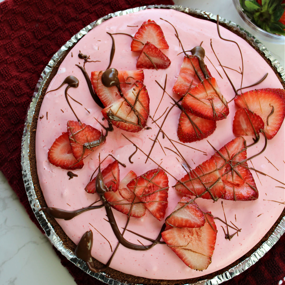 Strawberry pie with strawberries and drizzled chocolate on top.