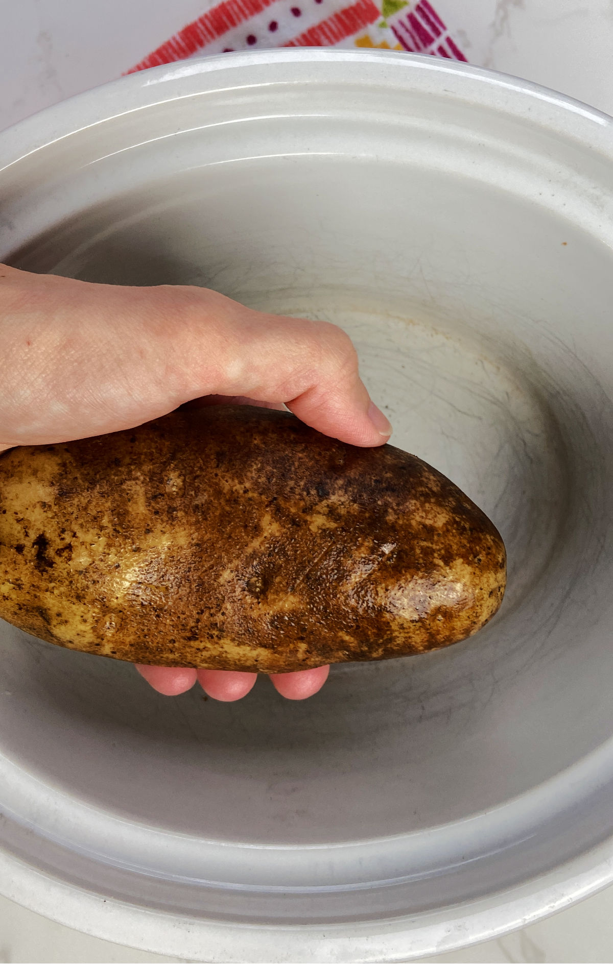 Potato over a white crock pot.