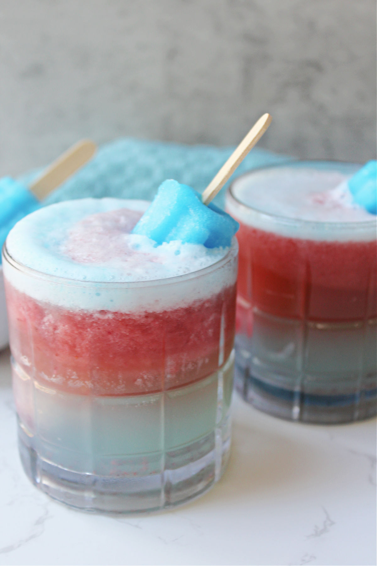 glasses of red, white and blue drink with bomb pops inside the glasses. 