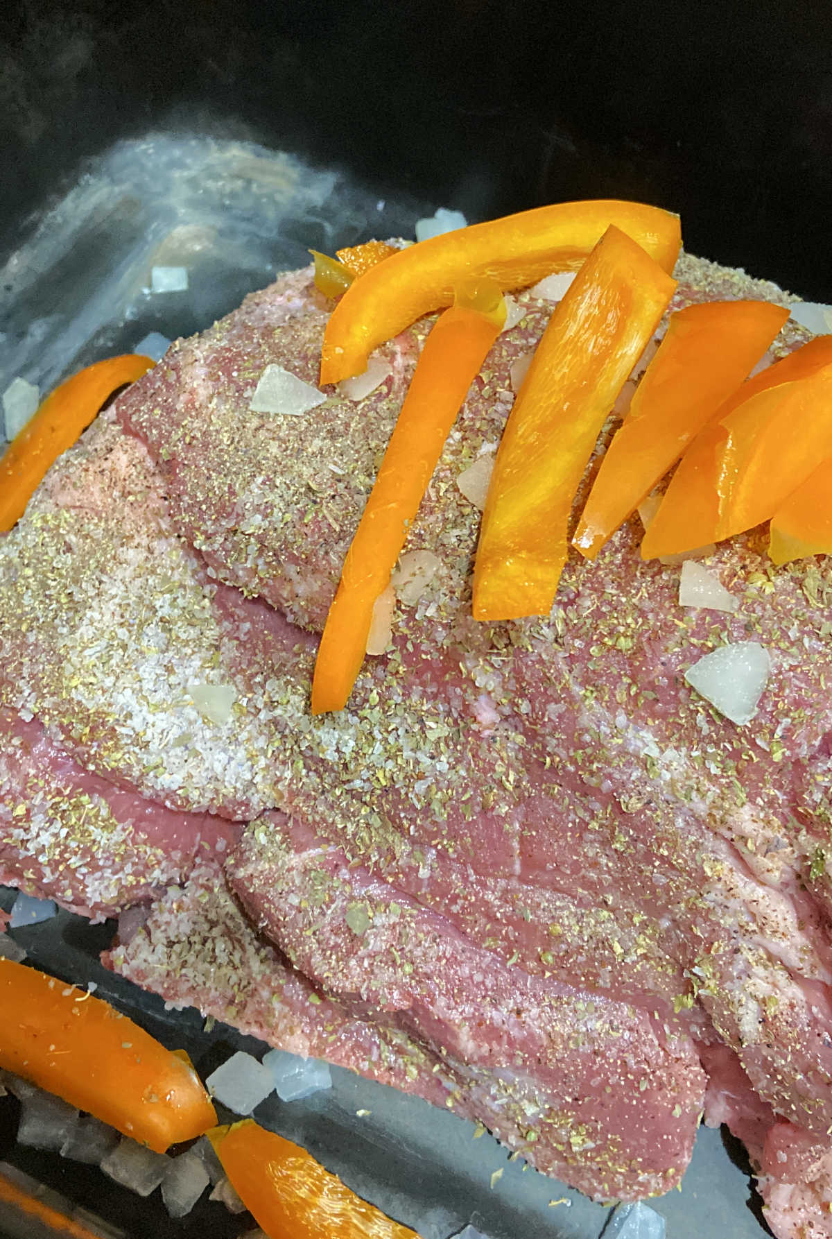 onions and peppers in a roaster with a pork shoulder. 