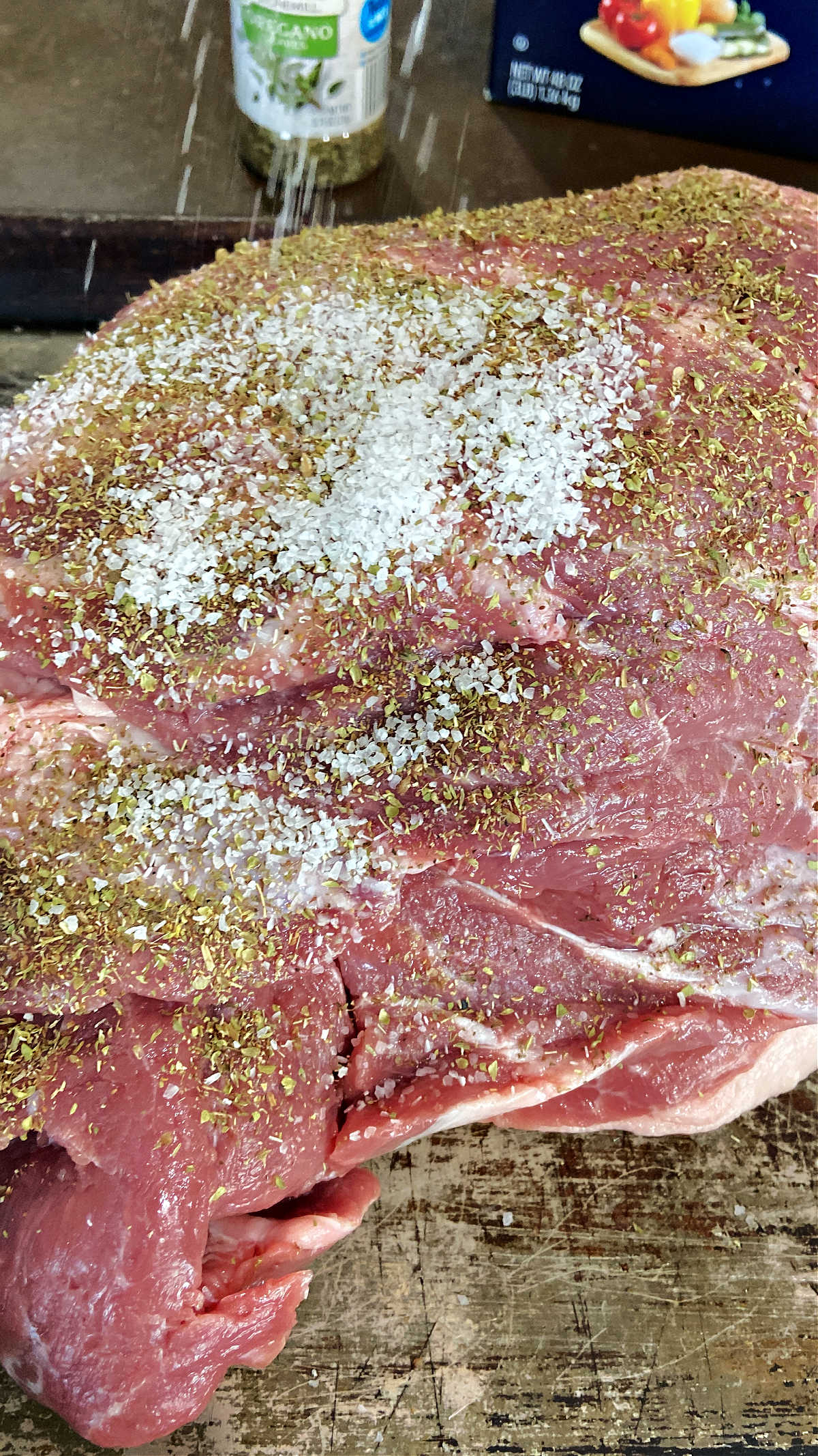 Salt being adding to the outside of a pork shoulder. 