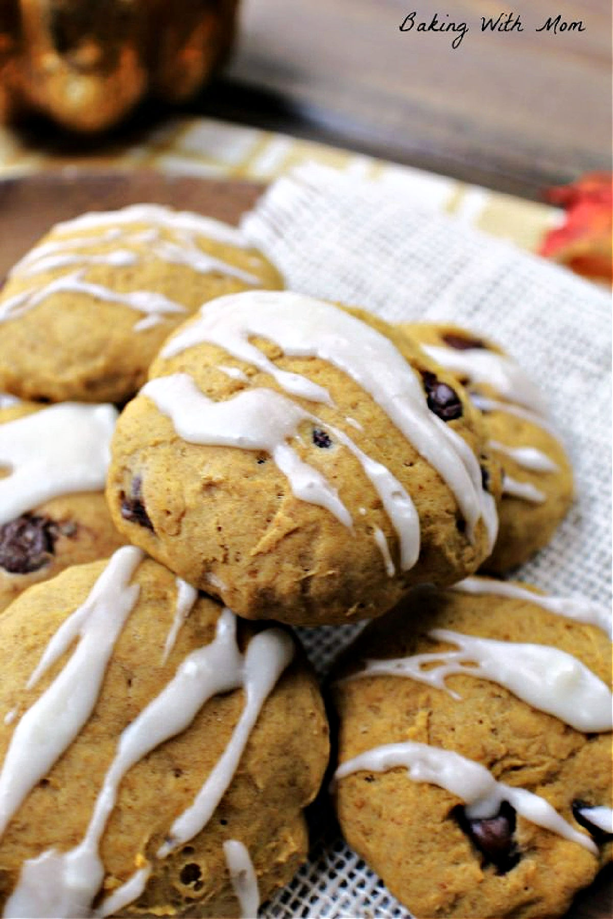 Plate of pumpkin chocolate chip cookies with white frosting drizzled on top. 