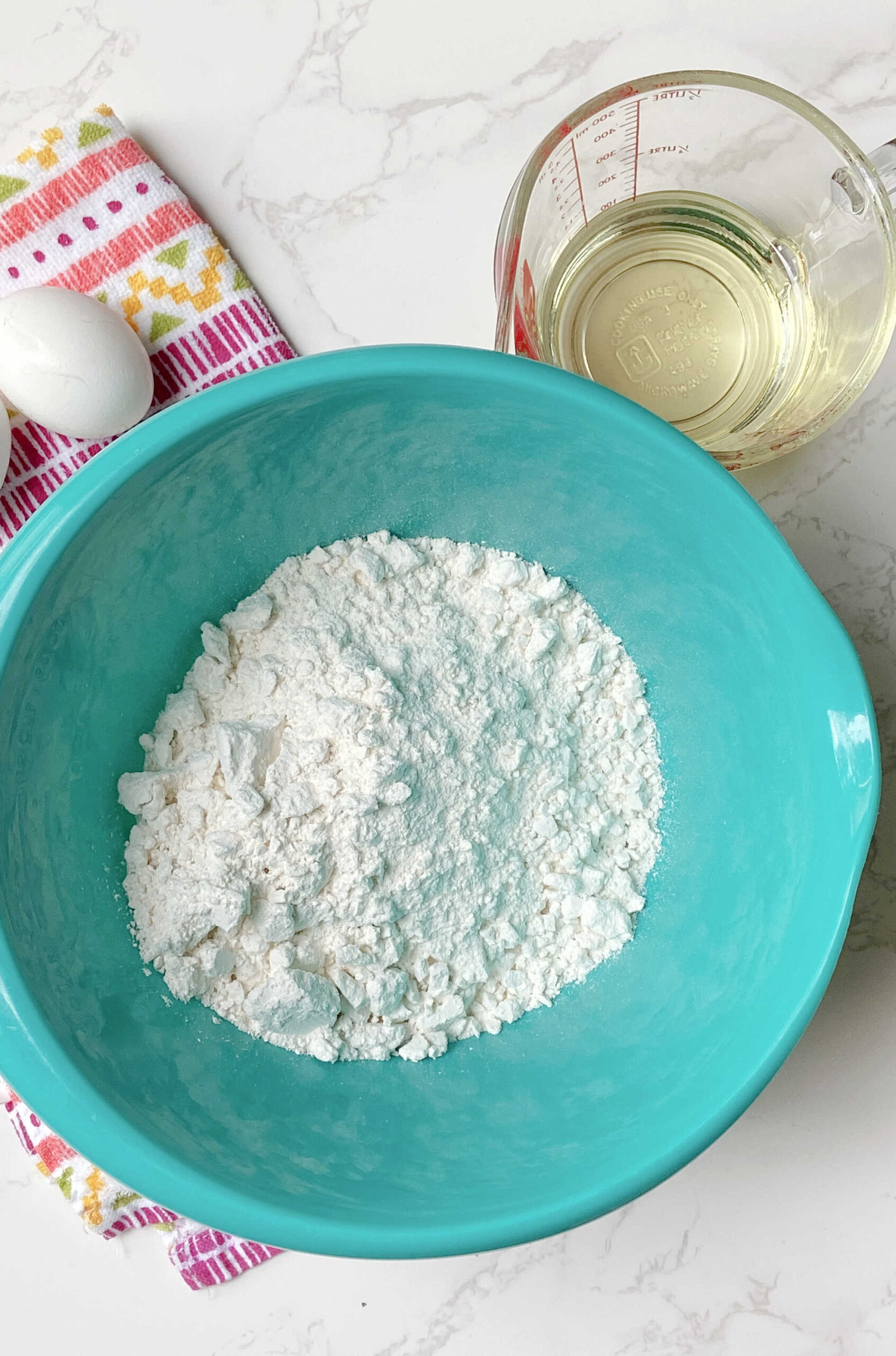 Dry cake mix in a blue bowl with a colored towel laying behind. 