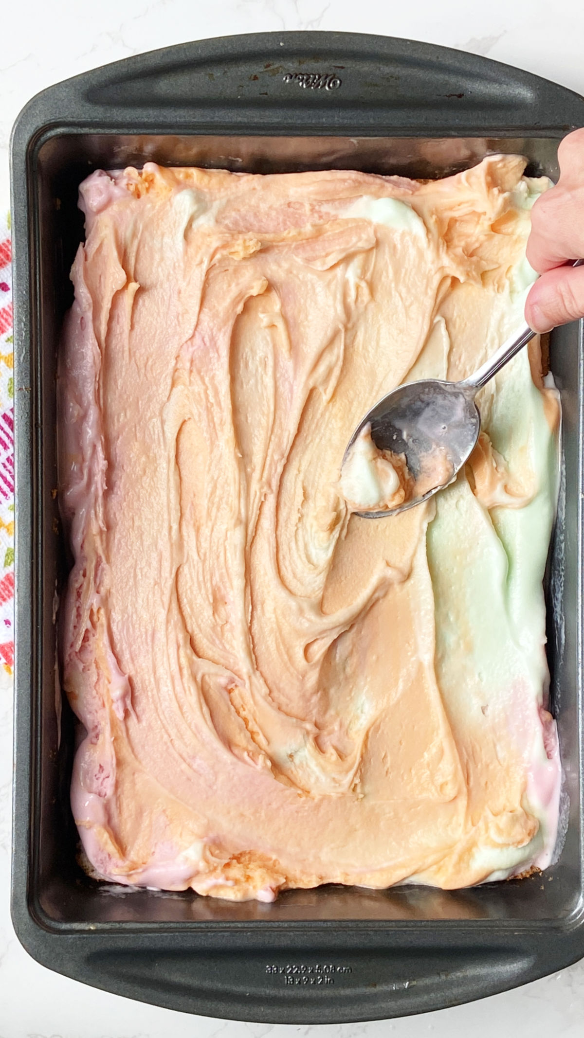 Softened rainbow sherbet in a cake pan. 