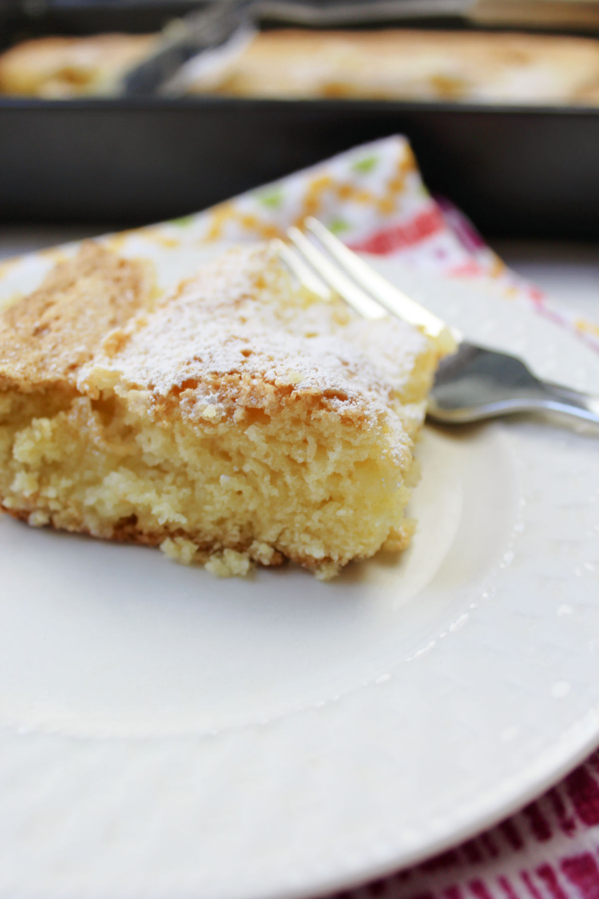 butter cake on a white plate with a cake pan behind. 