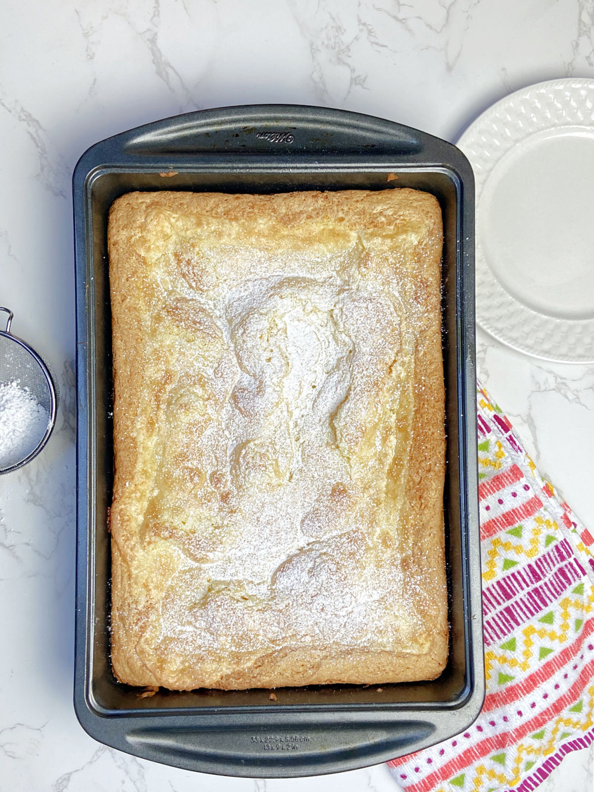 gooey cake in a cake pan with a multicolored towel besides. 