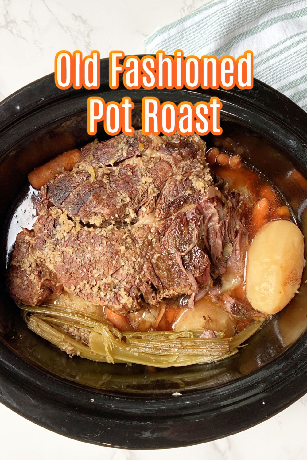 Pot roast in a crock pot with a green and white towel laying behind. 