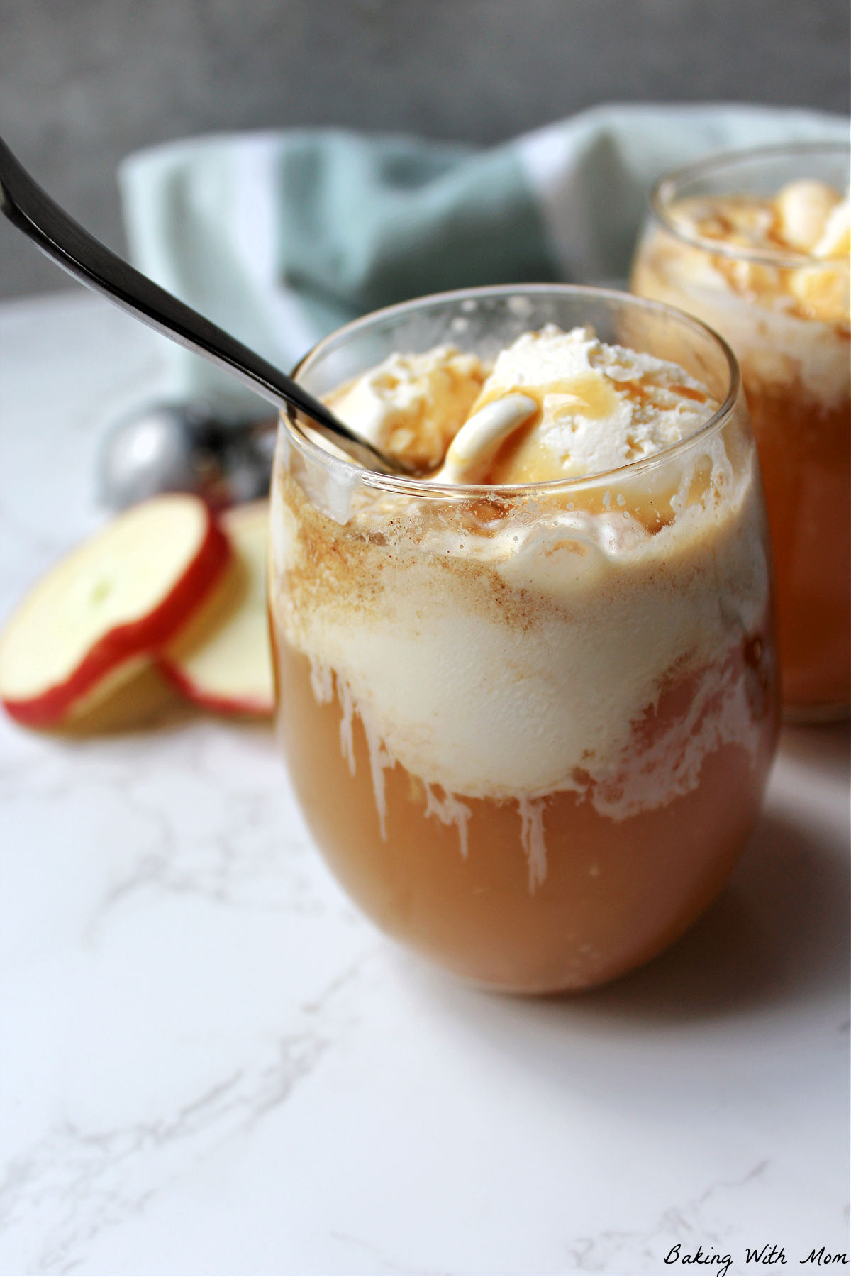 two glasses of apple cider with vanilla ice cream on top. 