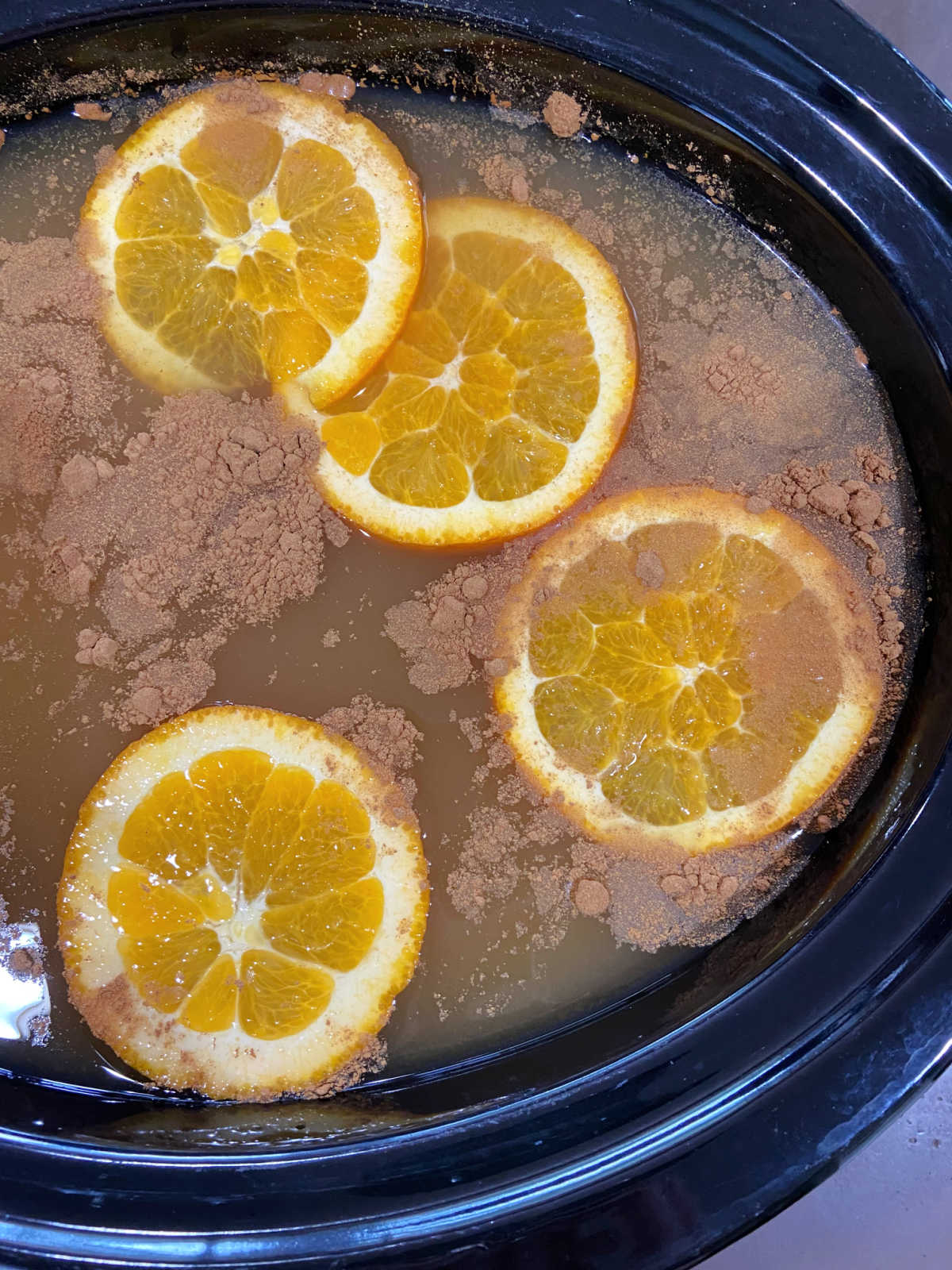 crock pot with apple cider, orange slices and cinnamon. 