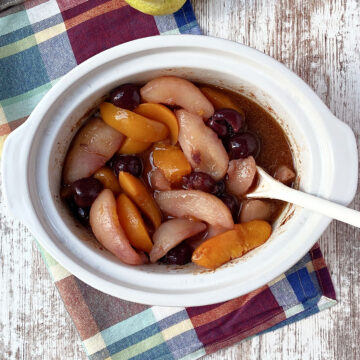 peaches, cherries and pears in a white crock pot.