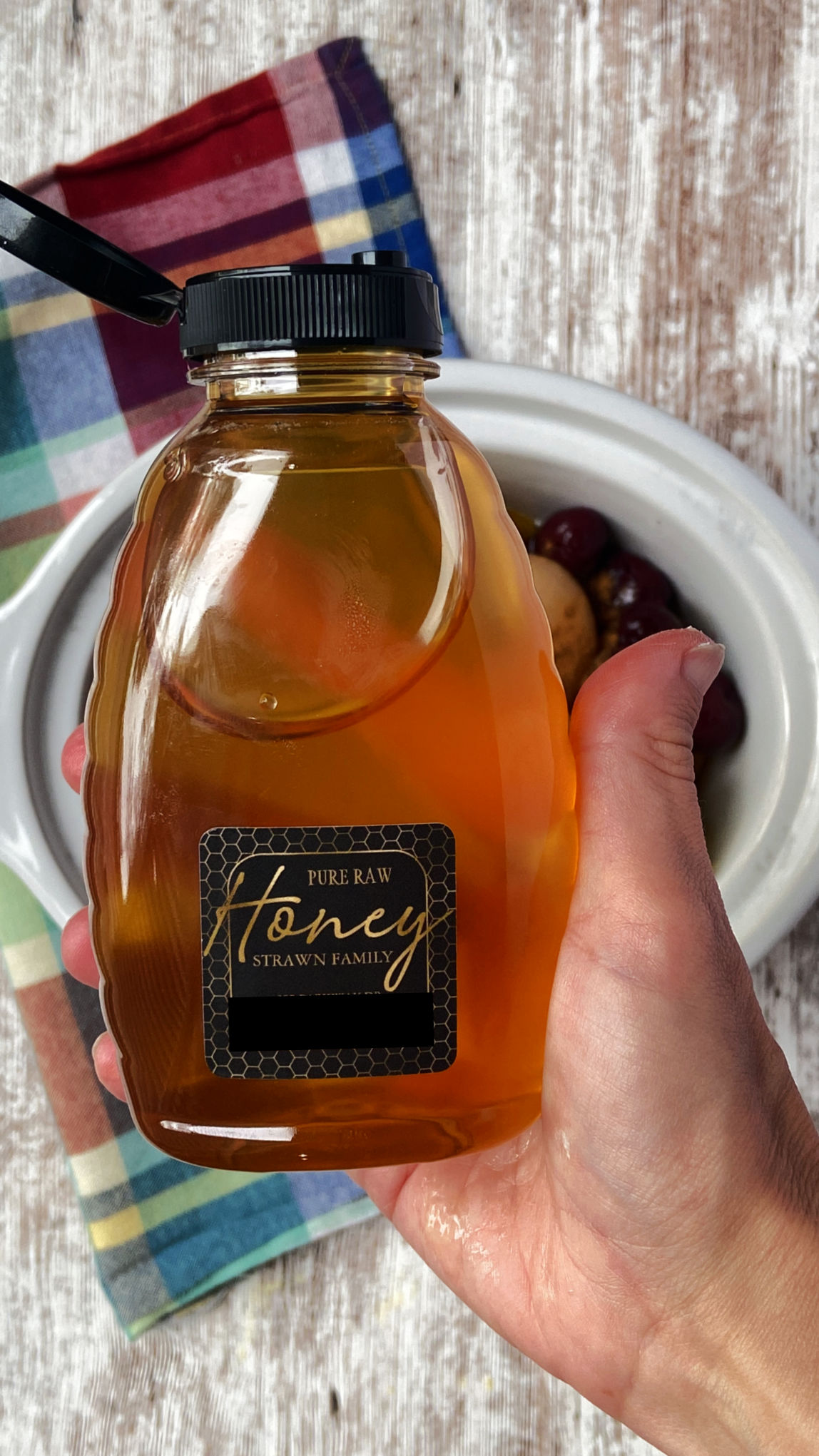 Hand holding a bottle of honey. 