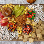 brown board with fruit, pretzels and cookies.