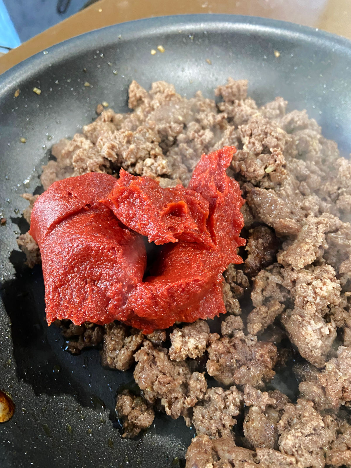 cooked hamburger in a frying pan with tomato paste
