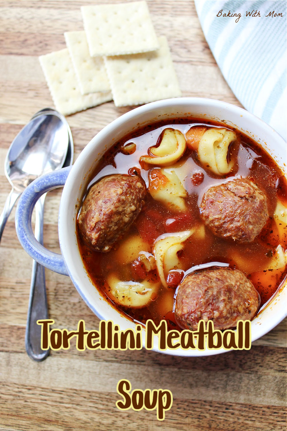 spicy meatball soup in a blue bowl next to crackers and a spoon. 