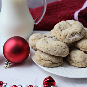 gingersnap cookies on a white plate with red Christmas decorations.