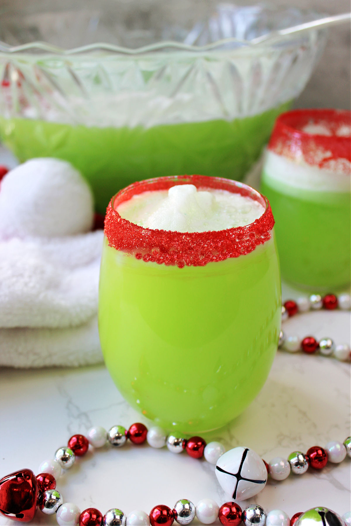 two glasses of grinch punch with red and white decorations. 