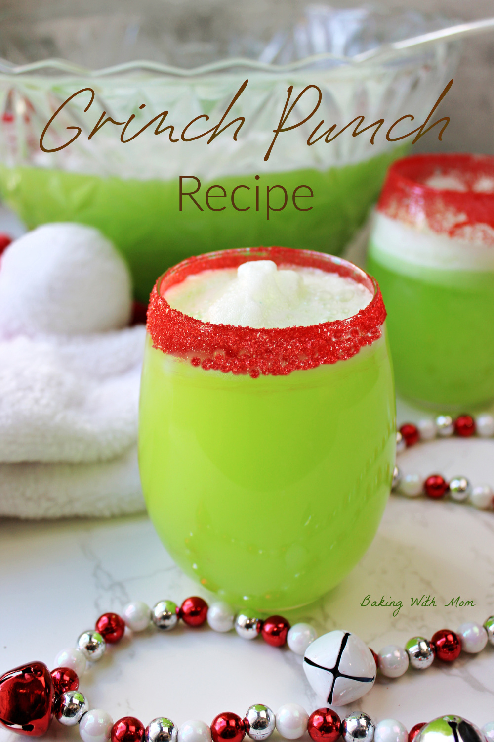 Grinch punch in a clear glass with red sanding sugar on rim. 