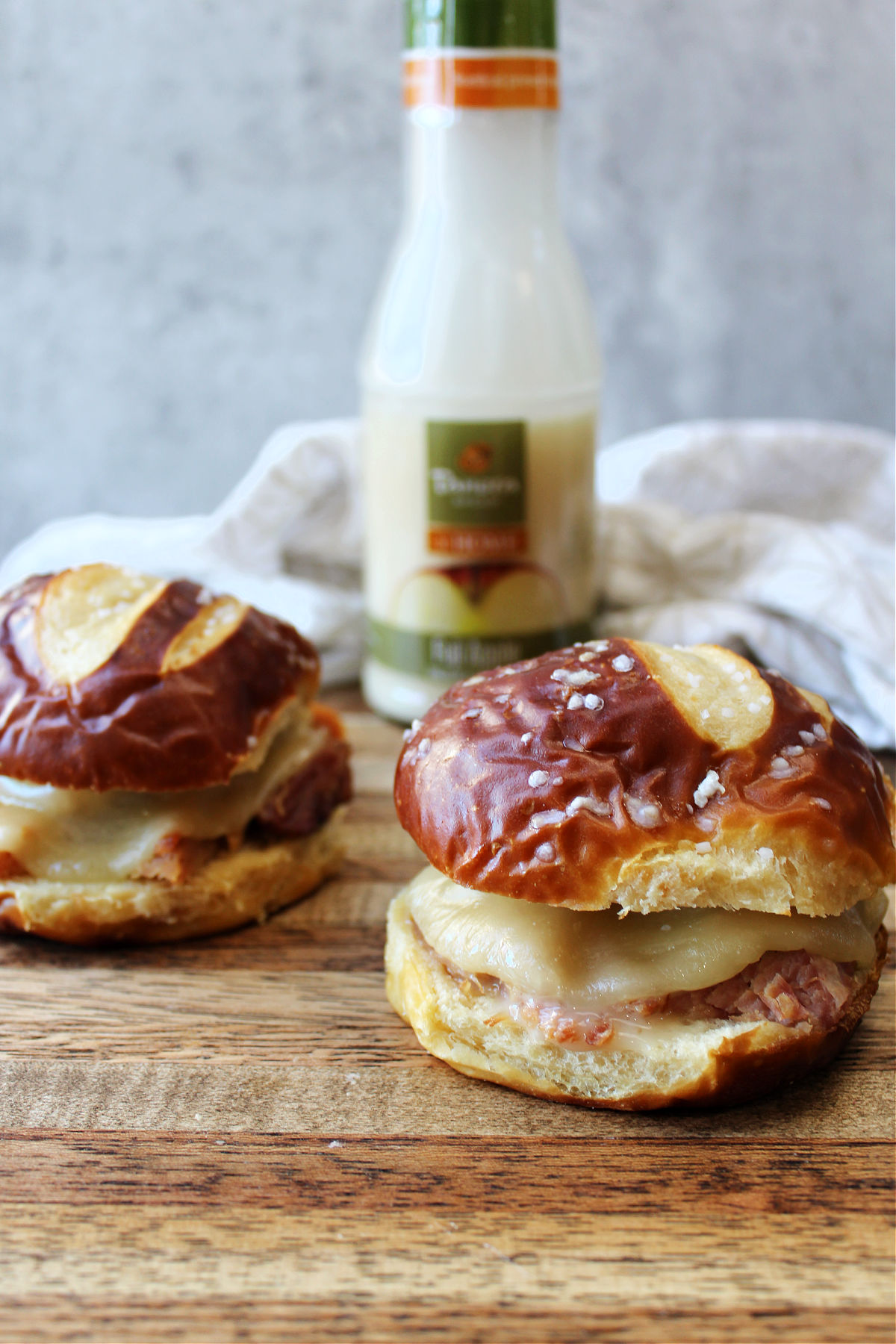 pretzel bun ham sandwiches on a wooden cutting board.  