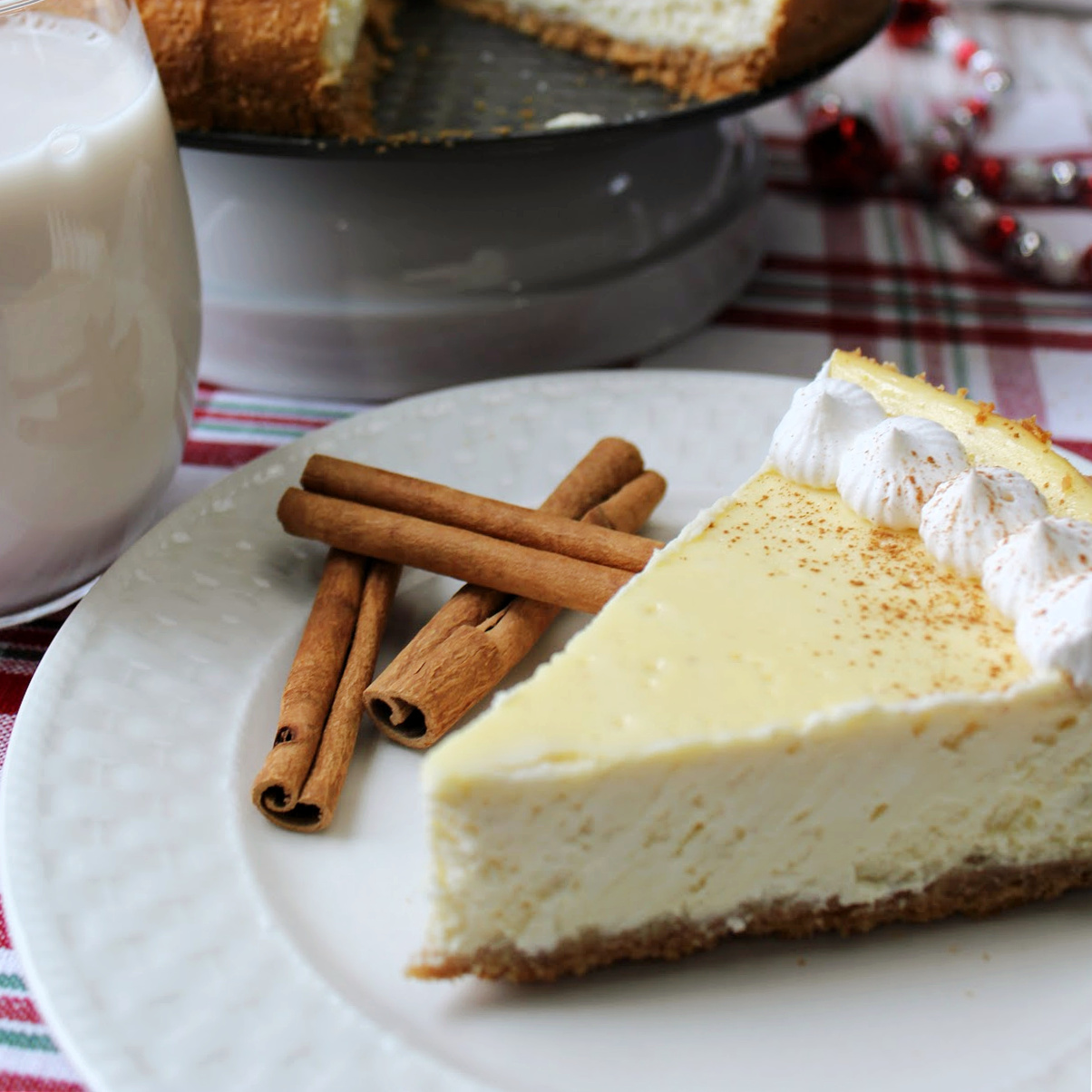 eggnog cheesecake on a white plate with a glass of milk besides.