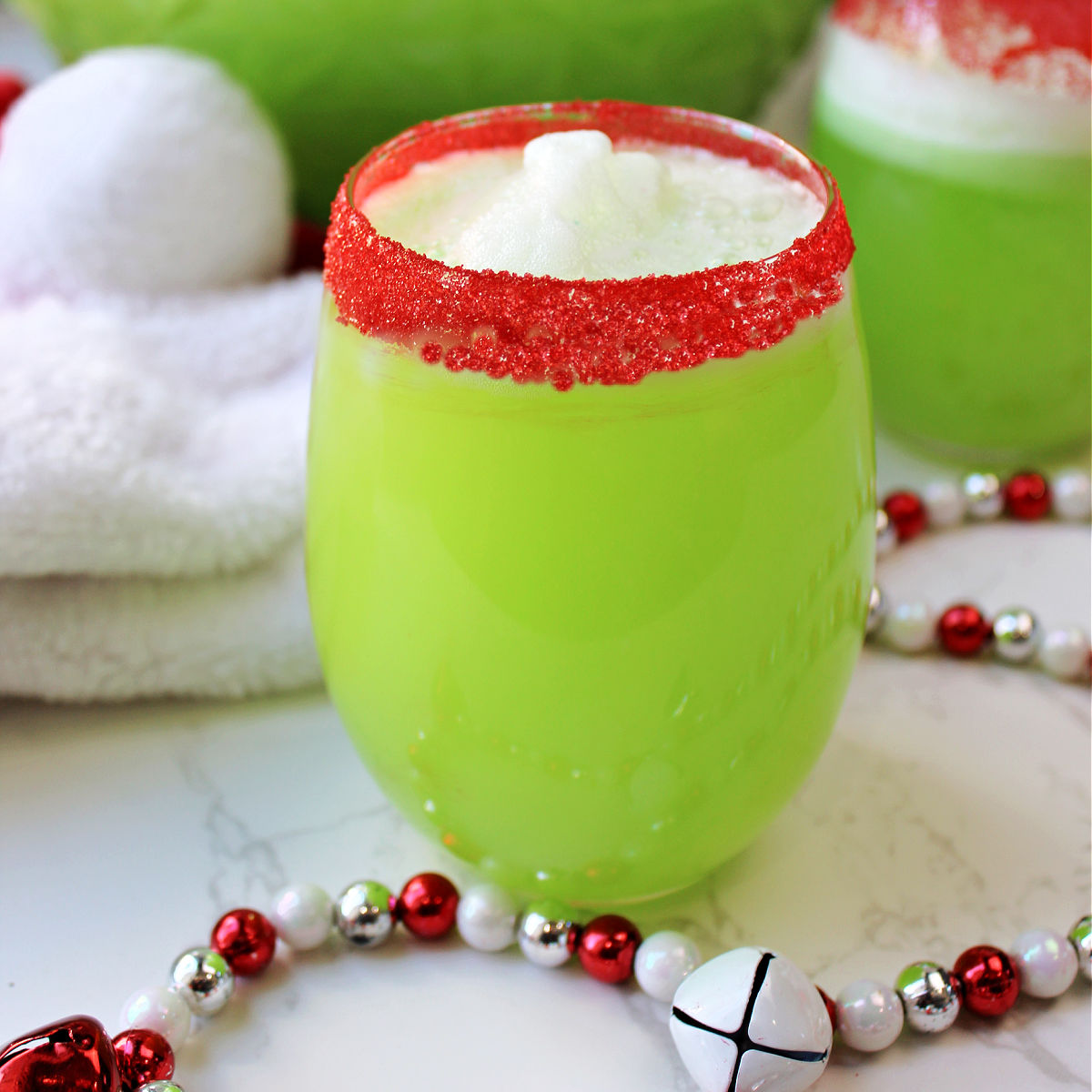 Grinch punch with Christmas decoration around the clear glass.