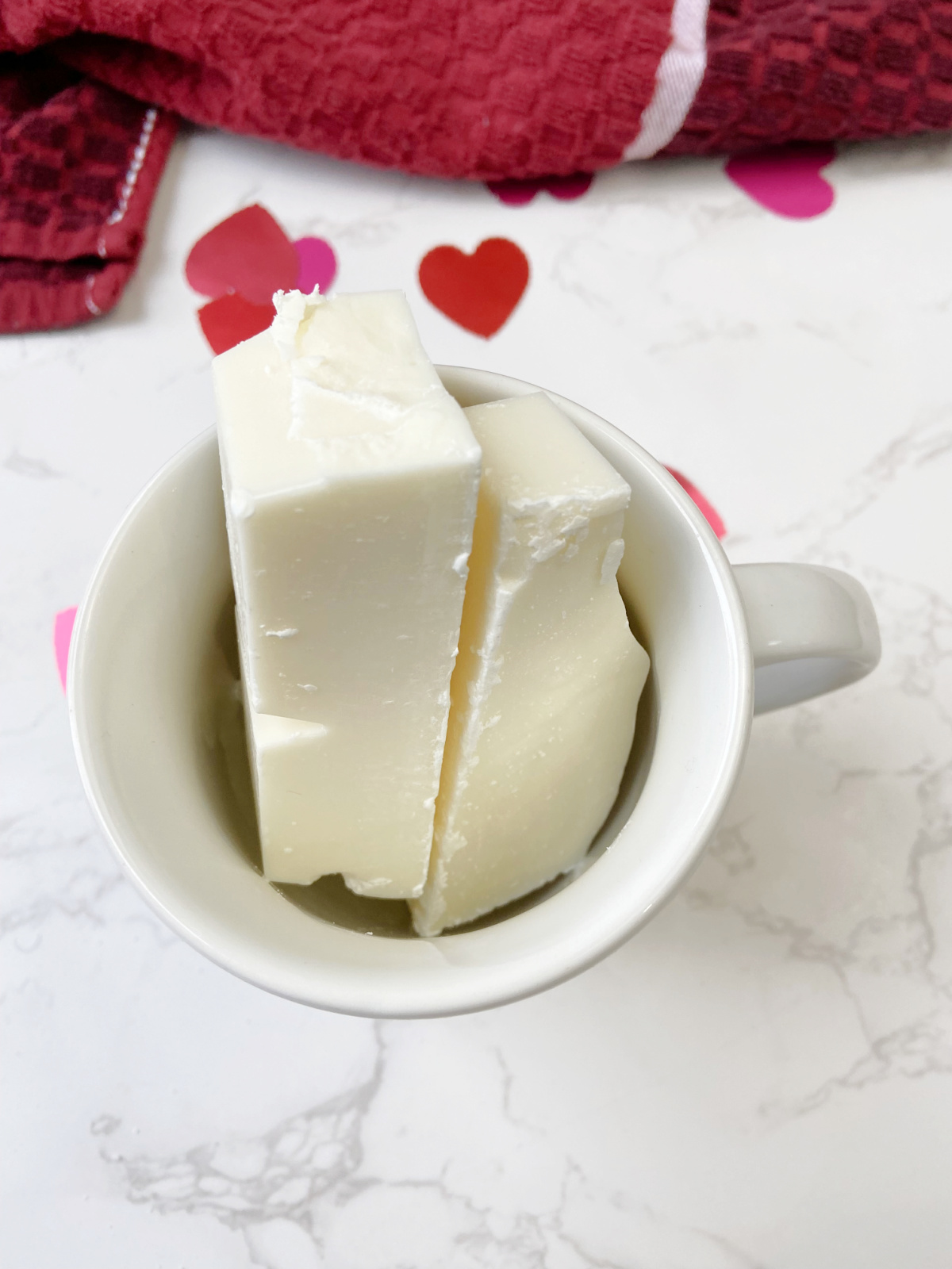 almond bark in a tall mug with a red towel. 