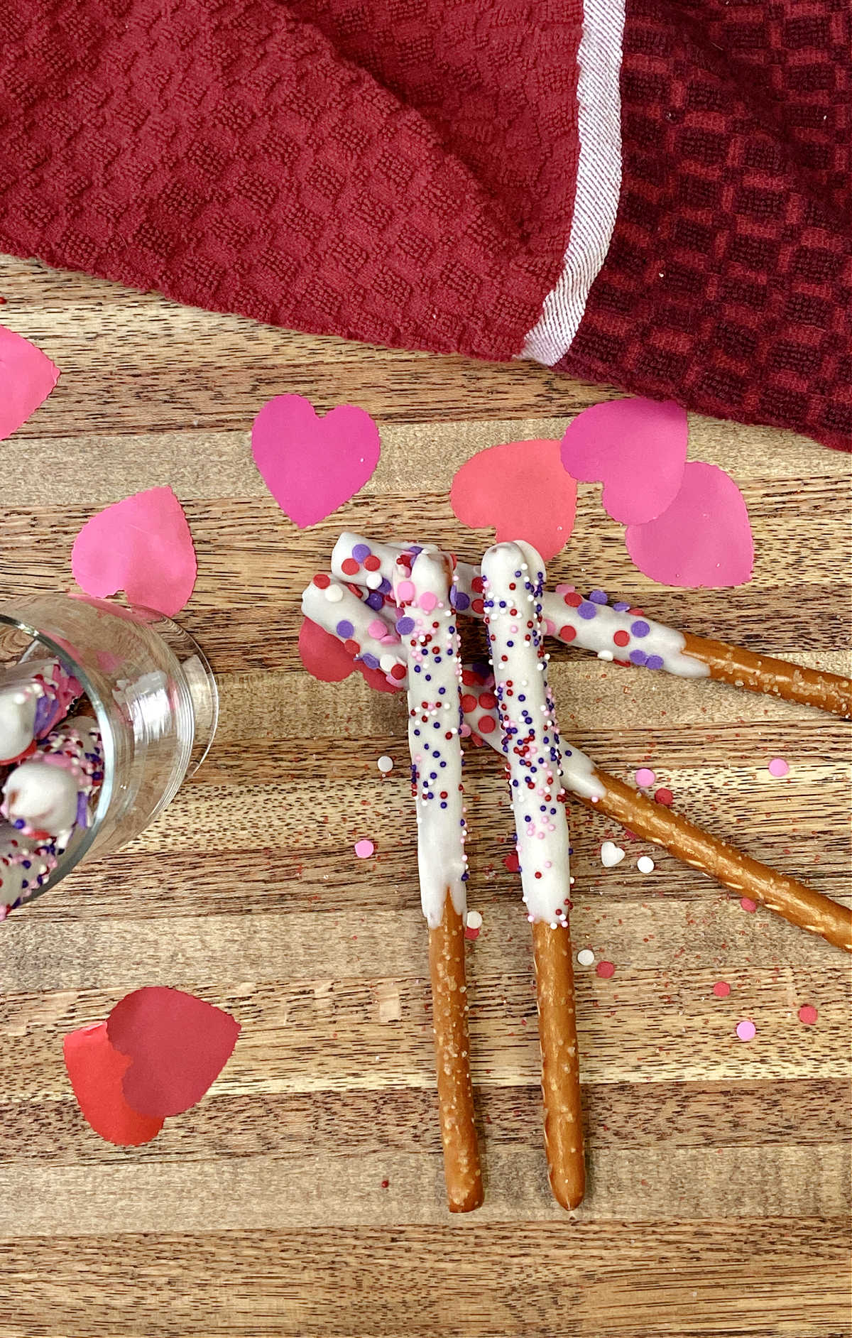 pretzel rods on a cutting board with red and pink hearts.