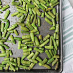 Oven roasted green beans on a baking sheet with salt and pepper.
