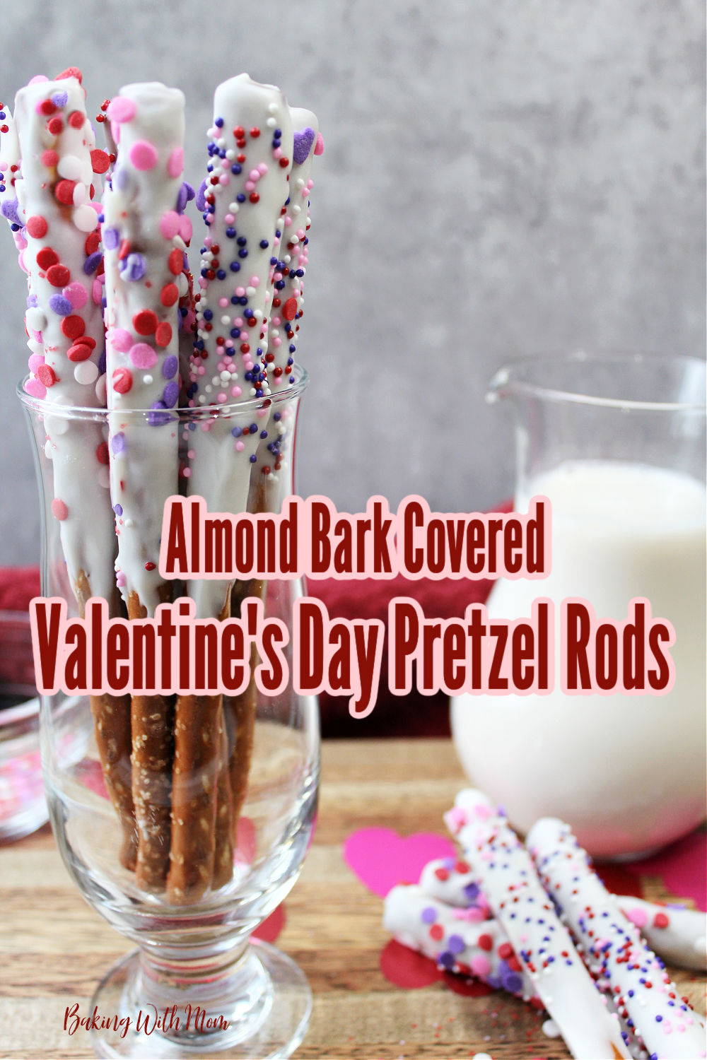 Valentine pretzel rods in a clear container with milk besides. 