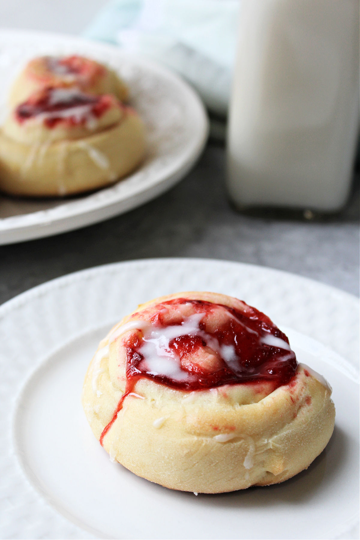 strawberry danish on a white plate with milk behind. 