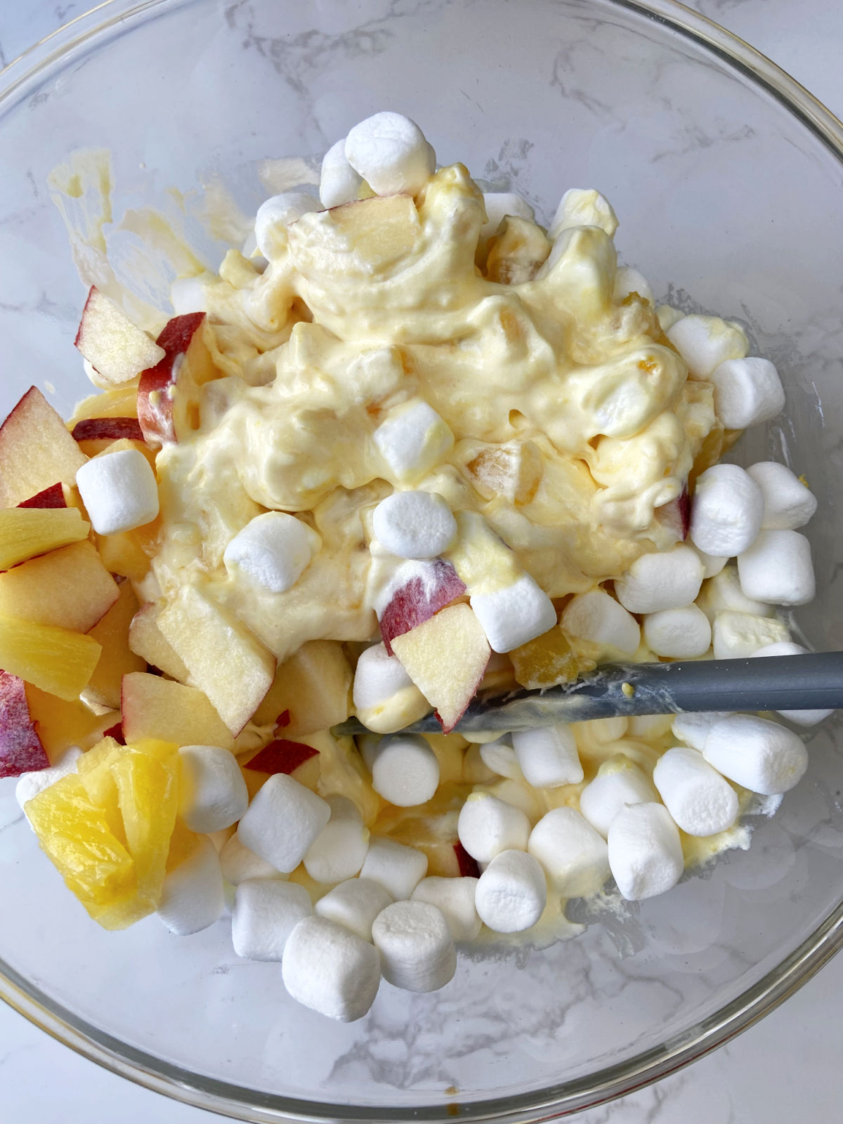 apples, marshmallows, pineapple in a bowl. 