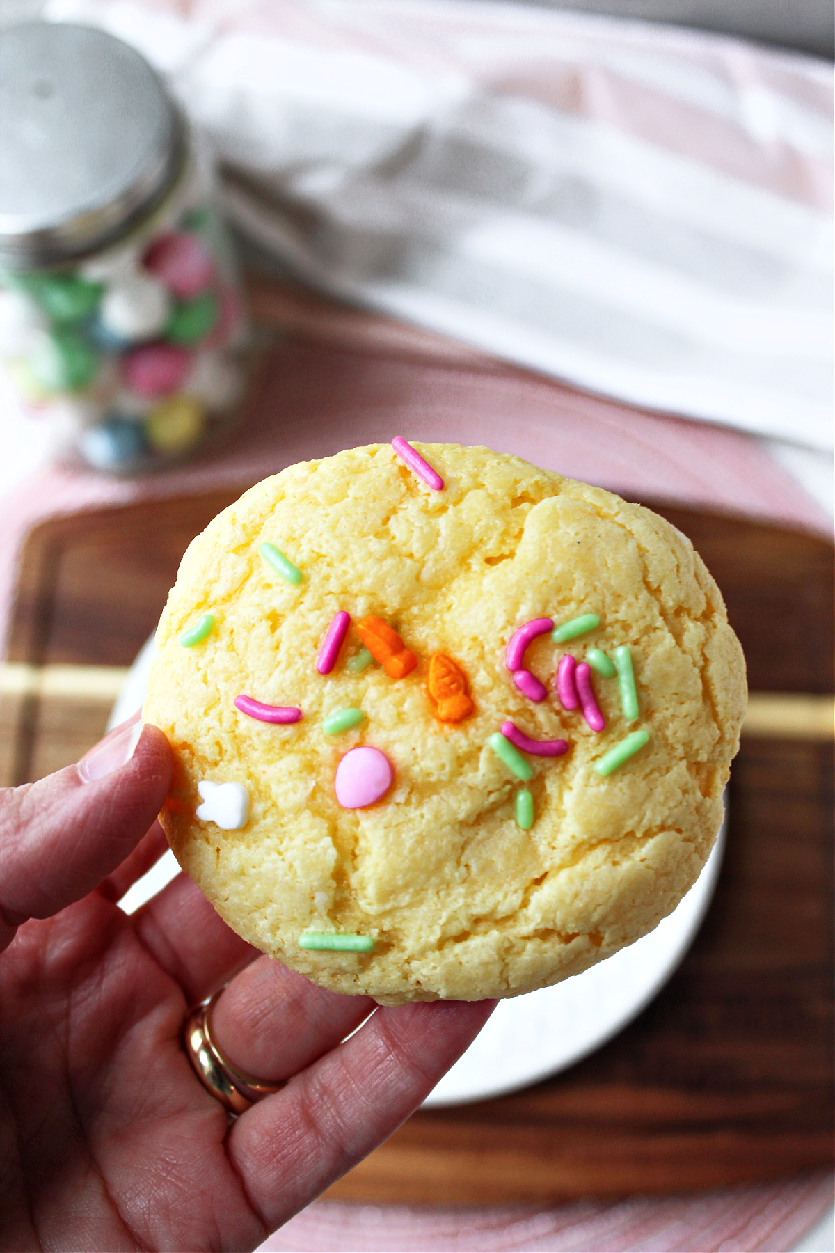 a hand holding a cookie with Easter sprinkles.