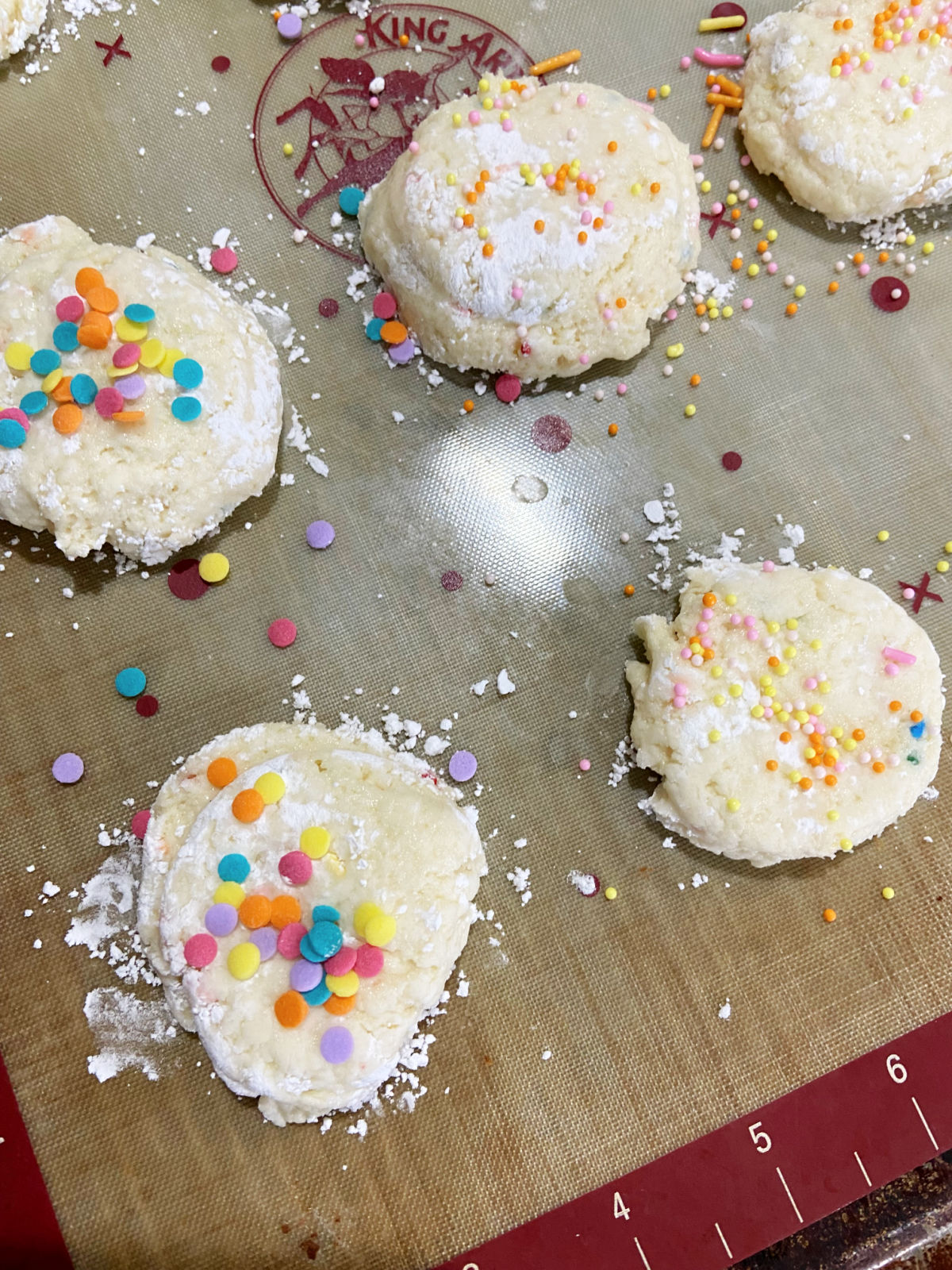 Uncooked cookies with sprinkles on a baking sheet. 