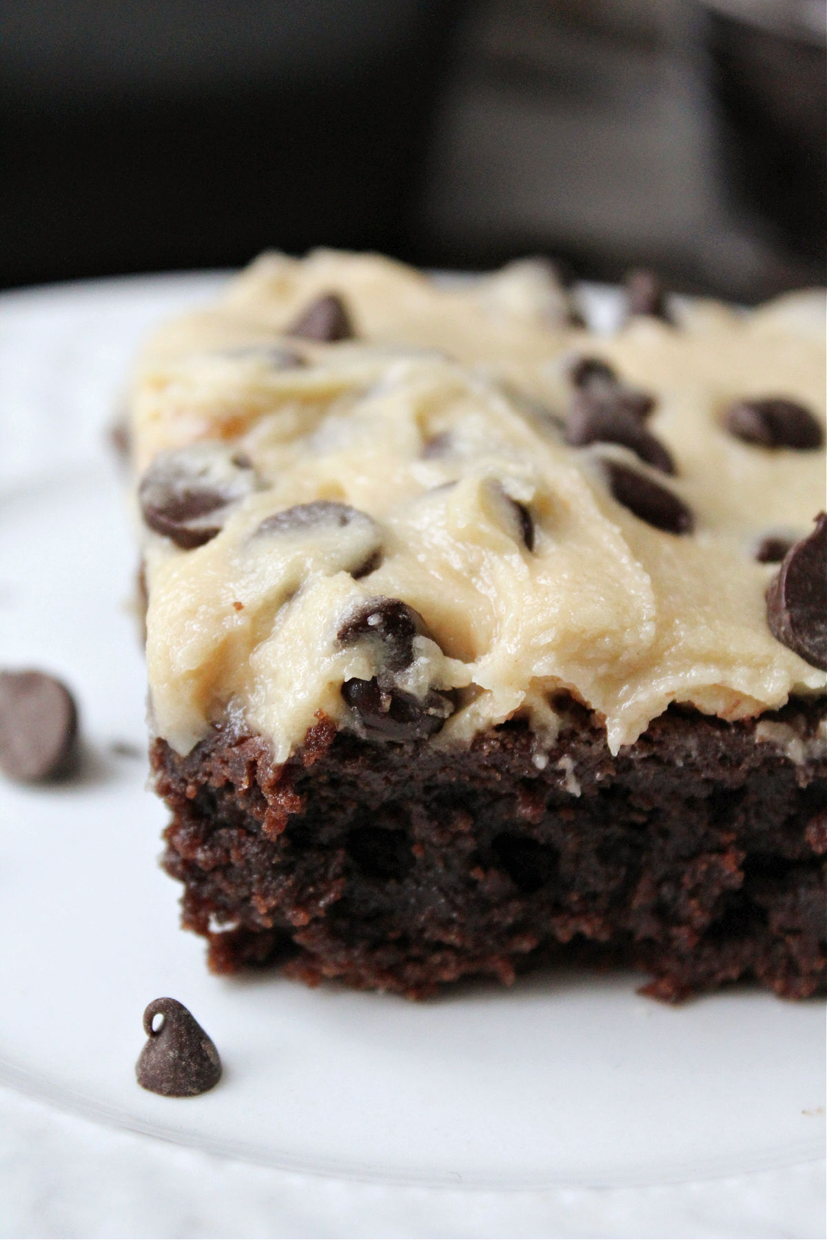 Brownie on a white plate with a cookie dough topping. 